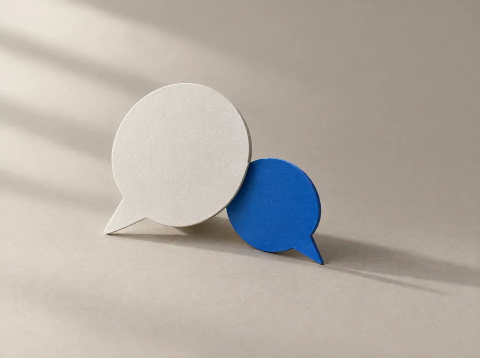 Zwei Sprechblasen aus Papier, eine weiß, eine blau